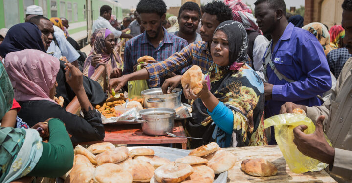 SHENDI, SUDAN - SEPTEMBER 09, 2021: Sudanese passengers buy sandwiches from a woman-owned food stall at Shendi railway station, Sudan.